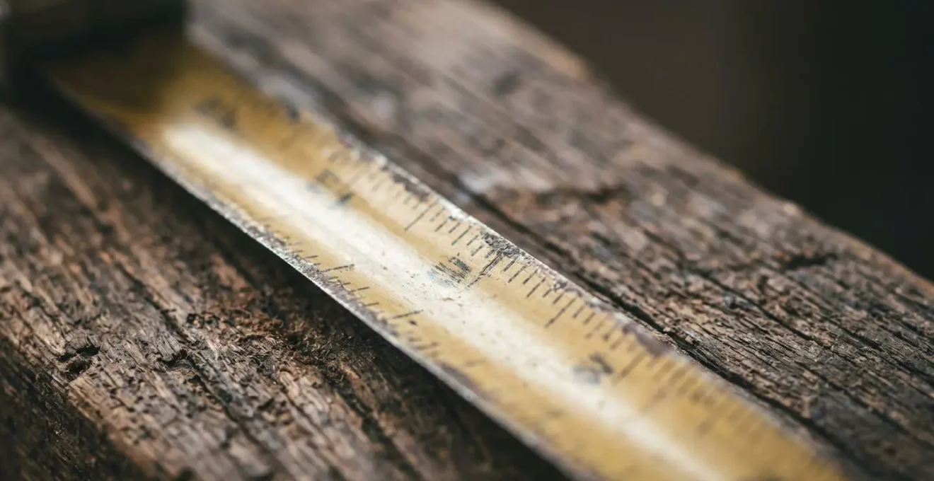 Dettaglio macro di metro da carpentiere su superficie in legno con luce naturale